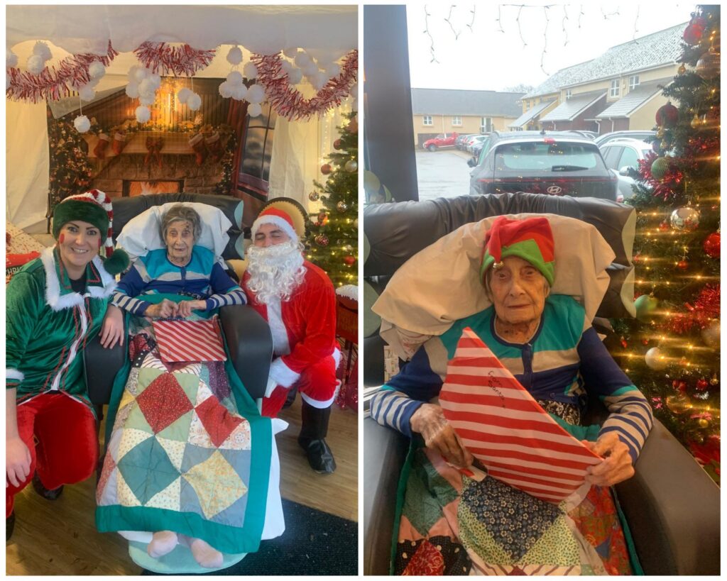 A Christmas-themed collage featuring an elderly woman seated in a padded chair with a festive quilt over her lap. On the left side, she is joined by two caregivers dressed as an elf and Santa Claus in a decorated room with tinsel and a holiday backdrop. On the right side, she sits beside a Christmas tree wearing a green-and-red elf hat and holding a red-and-white striped gift, with a snowy scene visible through the window behind her.